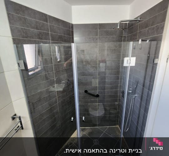 מקלחון זכוכית עם ראש מקלחת וקיר אריחים אפור